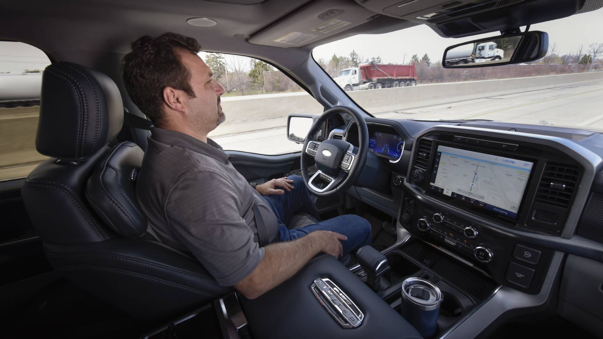 Mann sitzt im Auto am Steuer ohne Hände mit Ford Bluecruise Fahrassistenzsystem