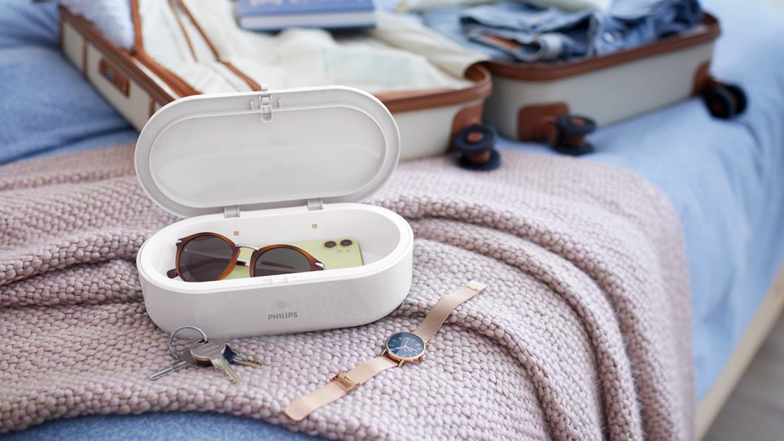 UV-C-Box mit Brille. Smartphone und Reisegepäck