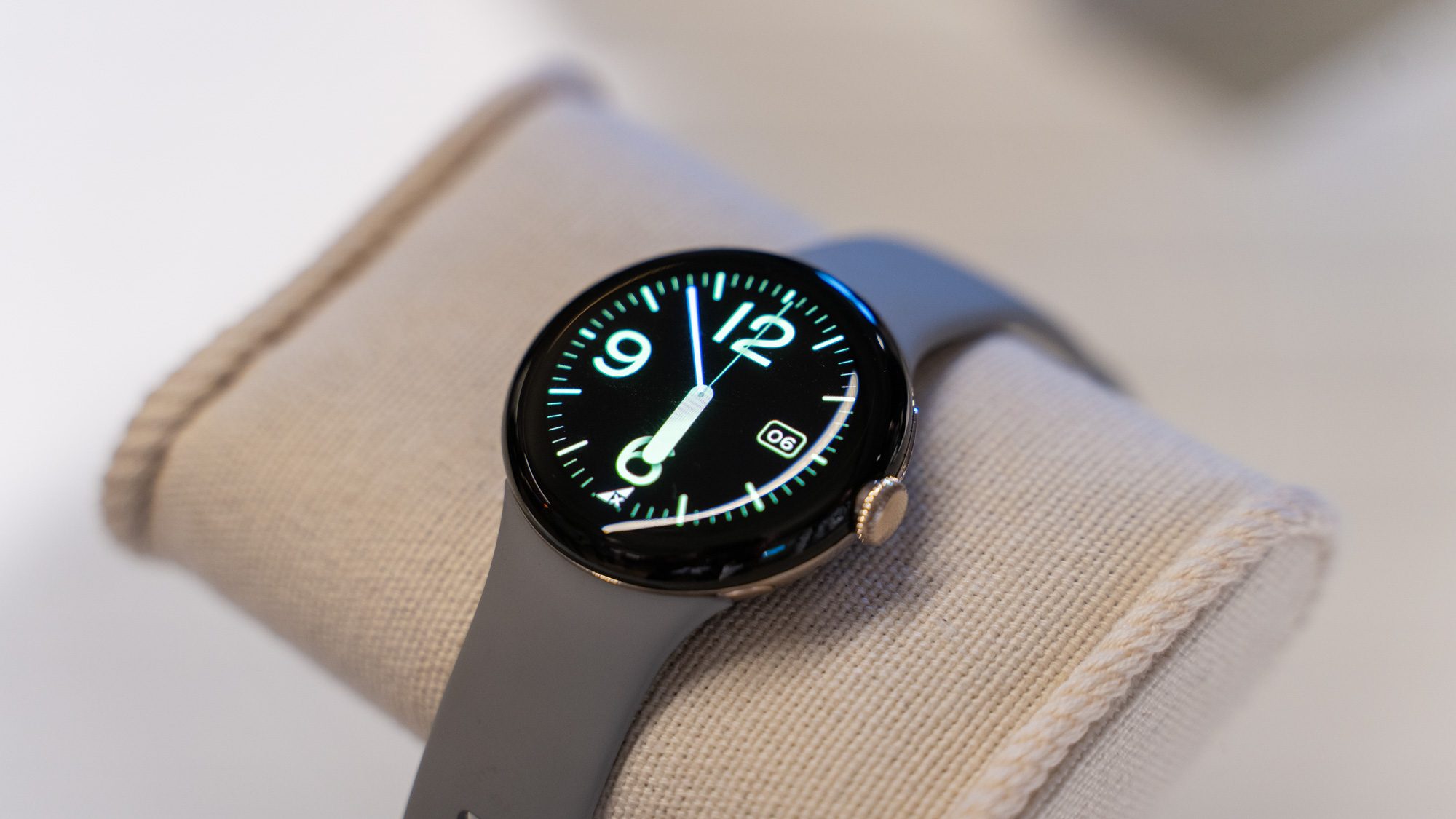 Google Pixel Watch Smartwatch, auf einem Stoffkissen liegend, mit eingeschaltetem Display.