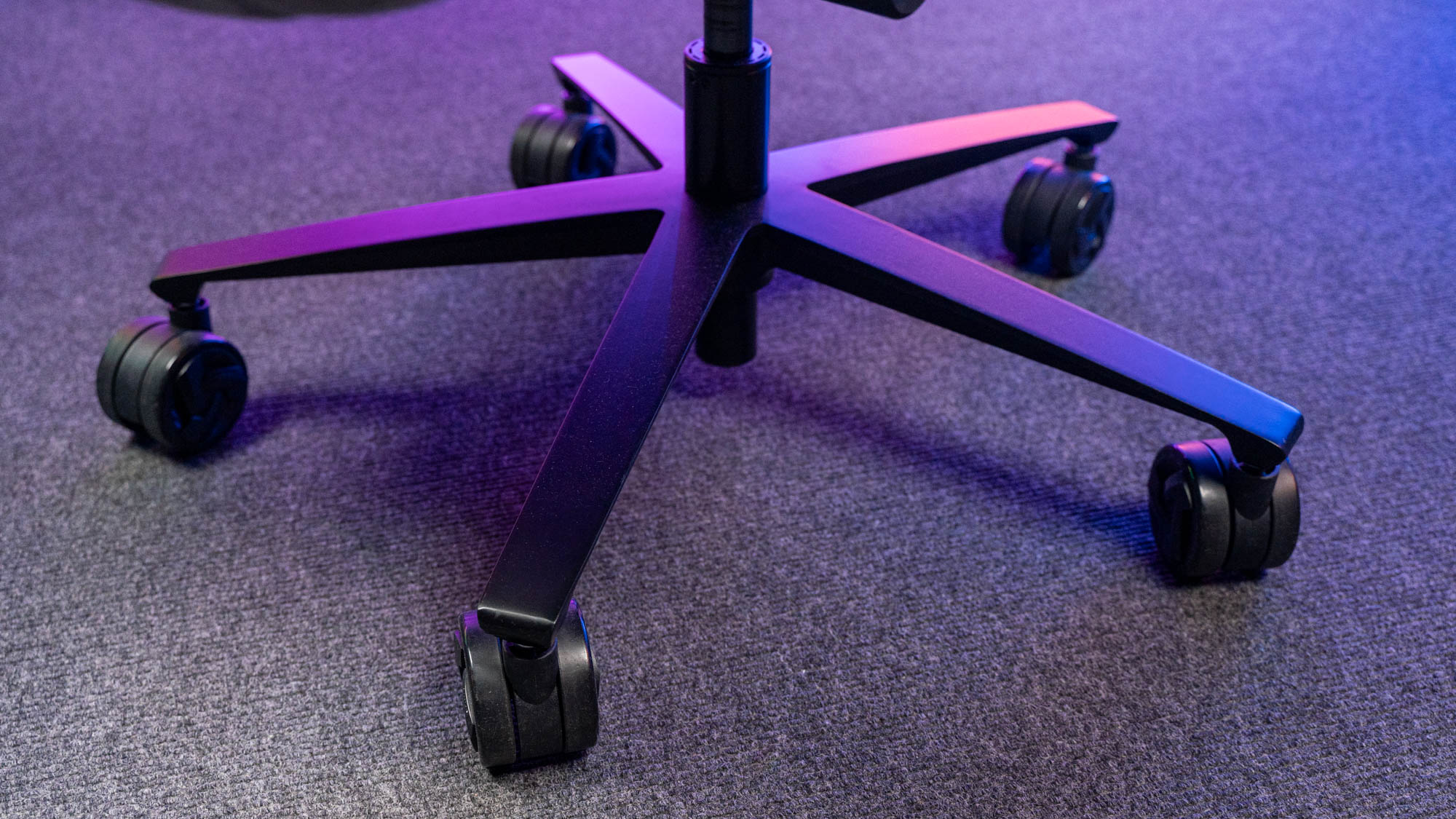 Schwarzes Metall-Fußkreuz eines Gaming-Stuhls mit PU-Rollen auf Teppichboden