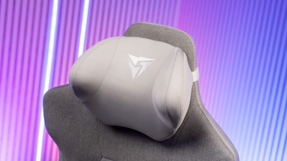 Graue Memory-Foam-Kopfstütze an Gaming-Stuhl mit Stoffbezug vor buntem Hintergrund