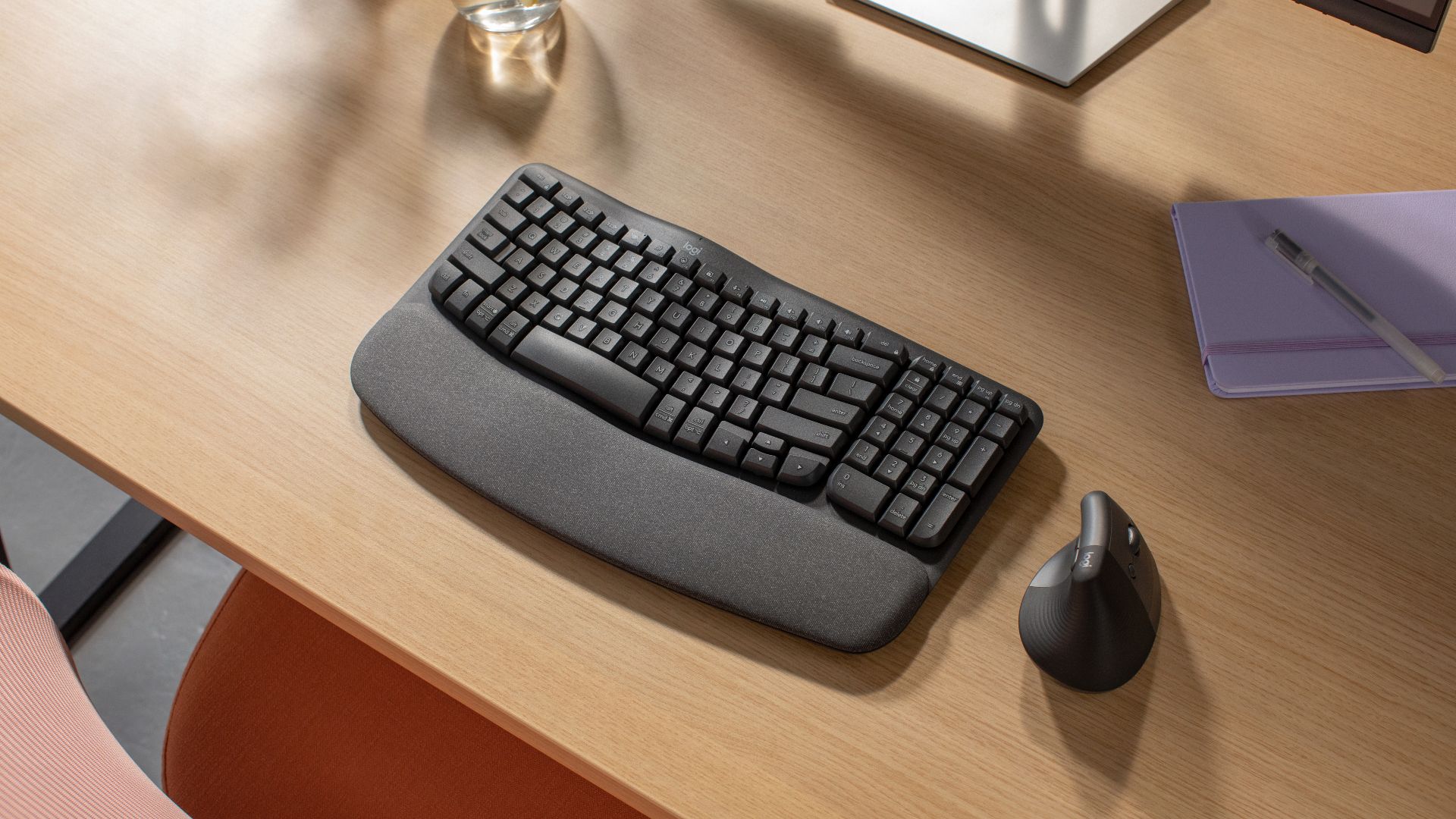 Logitech Wave Keys Tastatur auf Holztisch, daneben Lift-Maus.