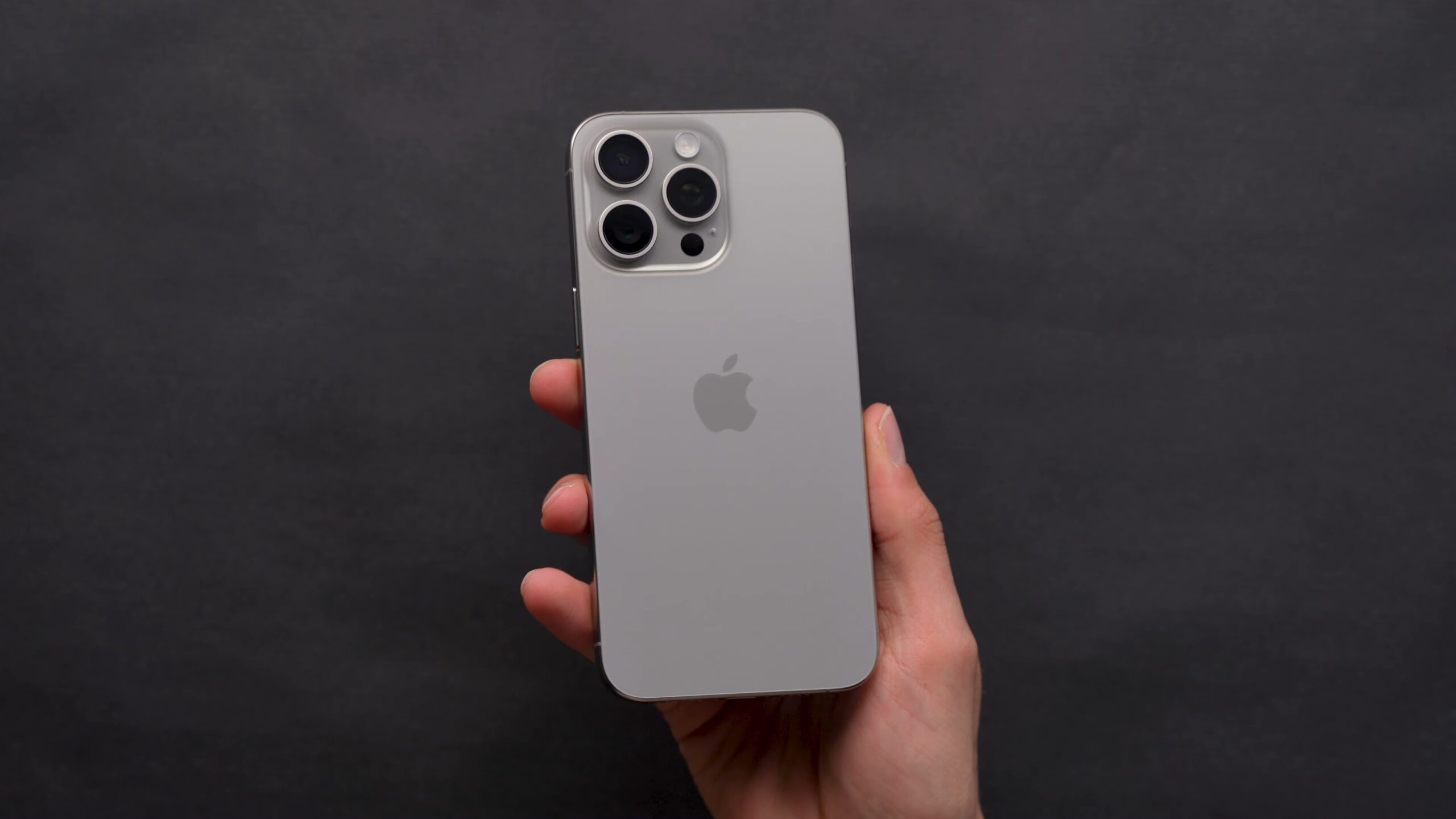Graue Rückseite eines iPhone 15 Pro Max in der Hand.