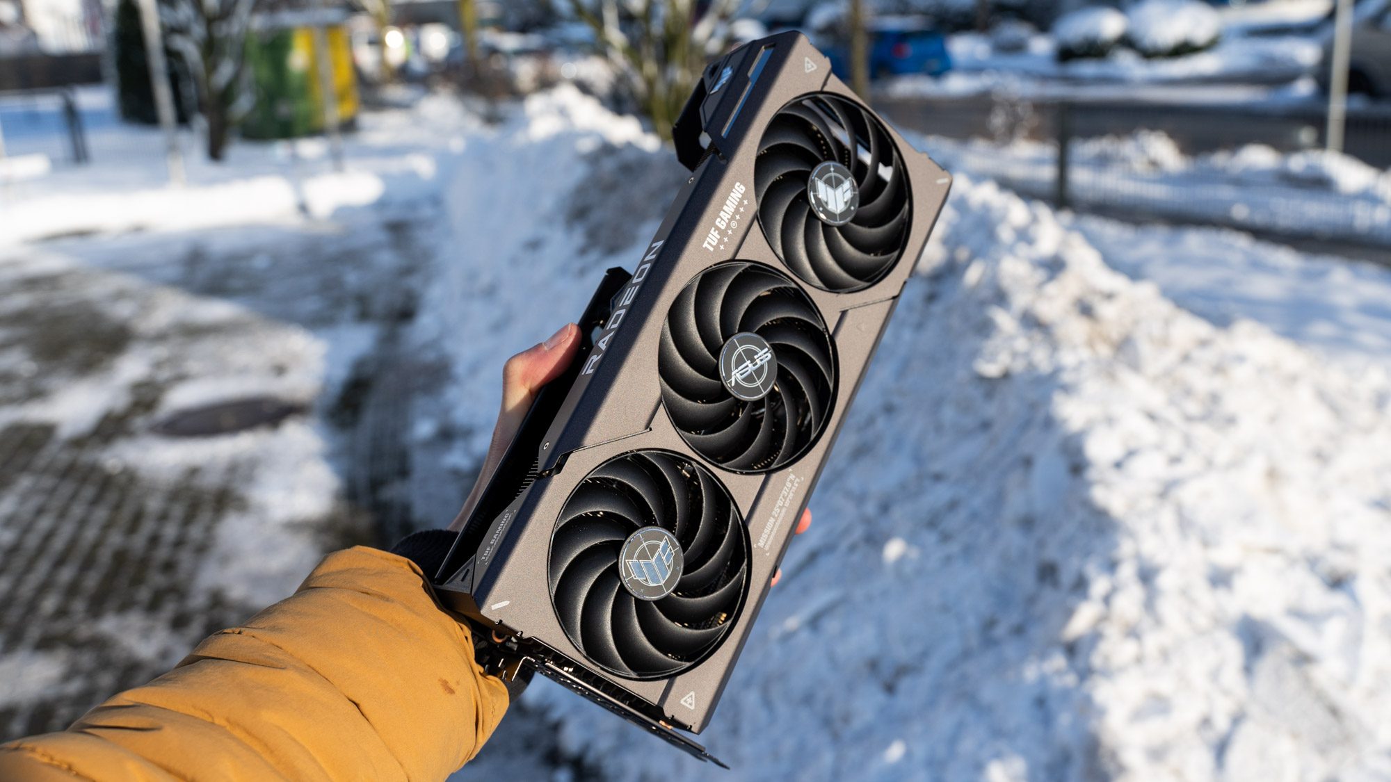 Asus TUF Gaming Radeon RX 7800 XT OC Grafikkarte in der Hand, Schnee im Hintergrund