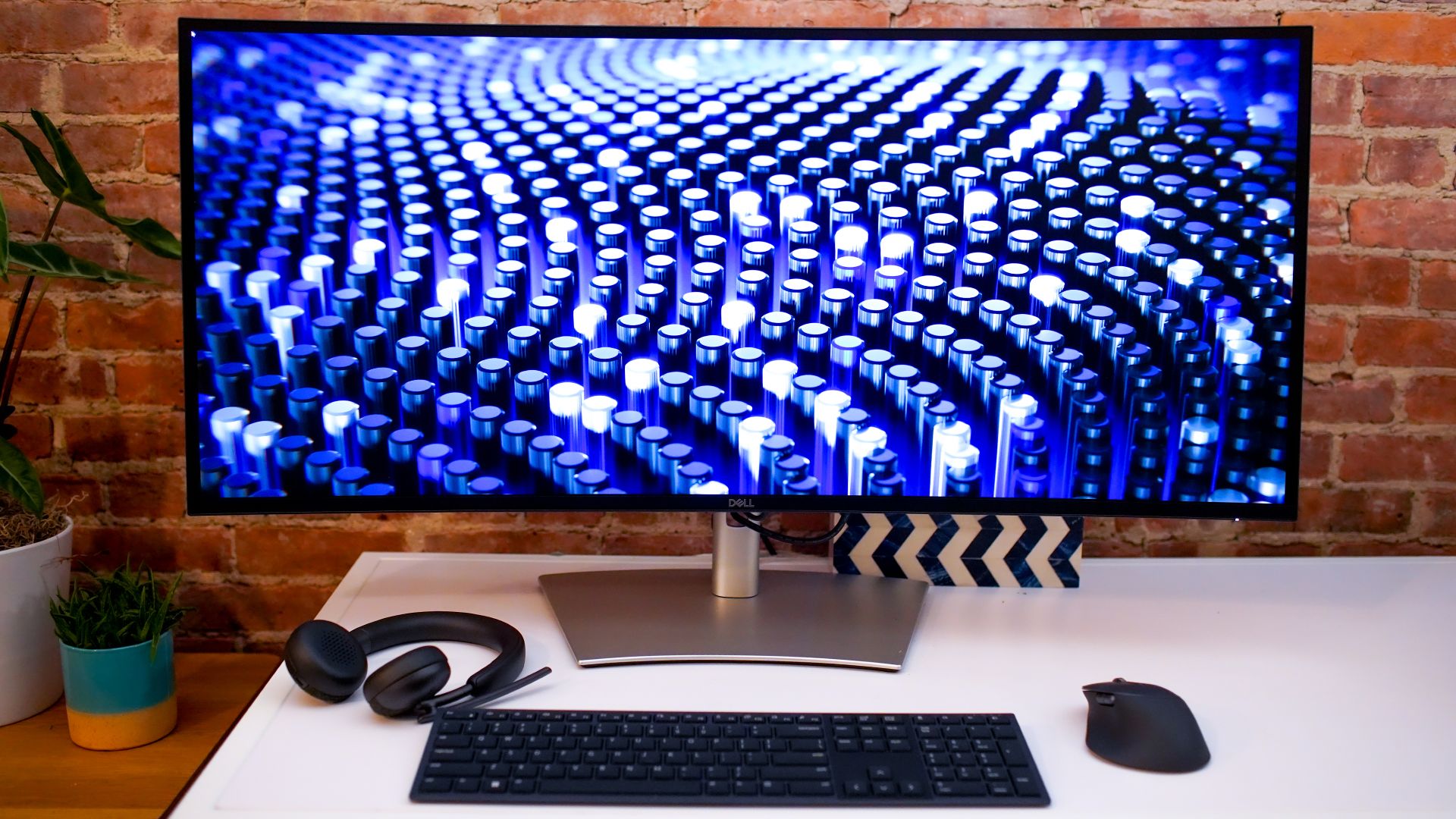 Dell UltraSharp U4025QW auf einem Schreibtisch mit Tastatur, Kopfhörer und Maus.