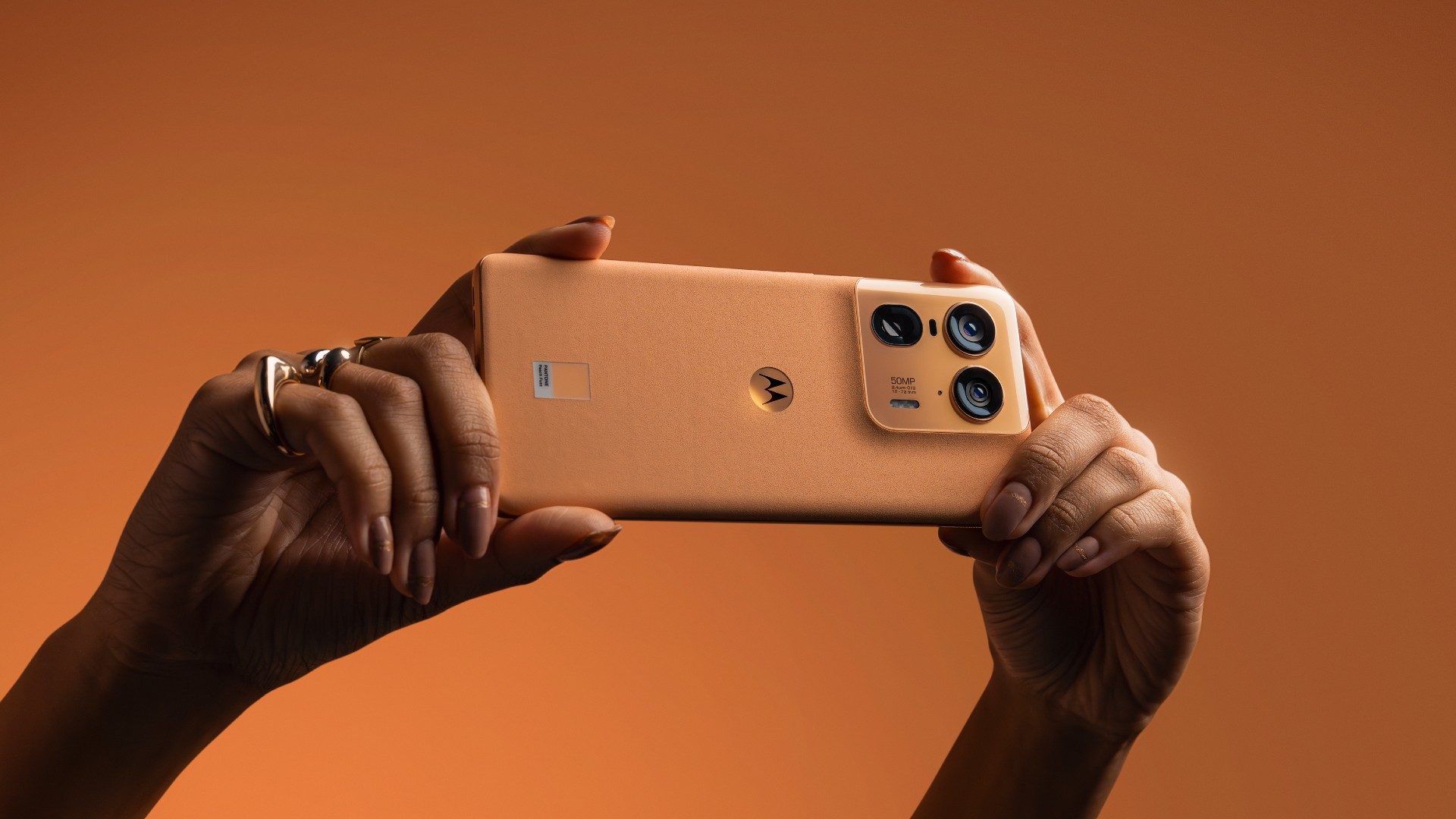 Zwei Hände halten Motorola Edge 50 Ultra in der Farbe Peach Fuzz